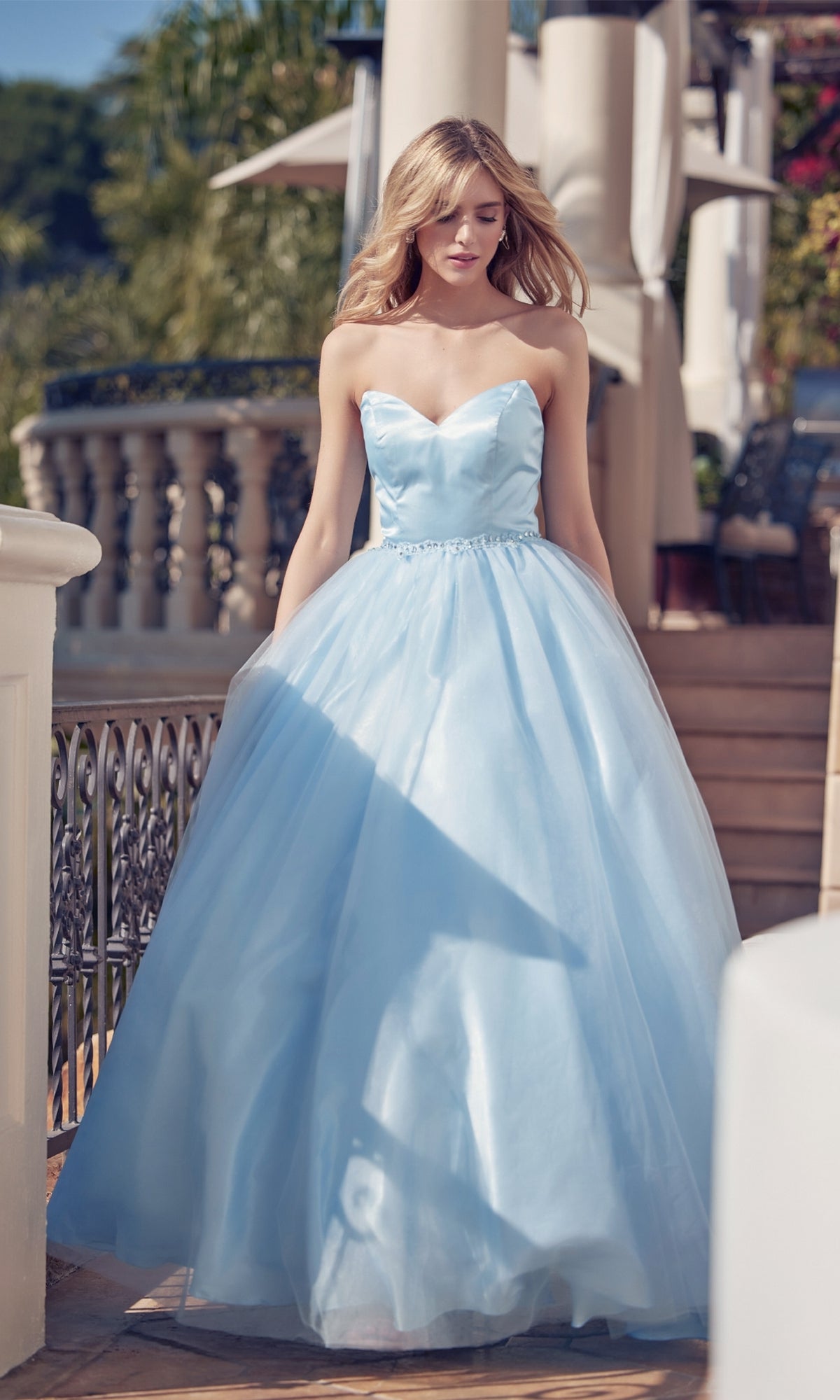 A woman in the Strapless Sweetheart Long Prom Ball Gown 265 with a corset back stands outdoors by a white railing and columns, greenery behind her.